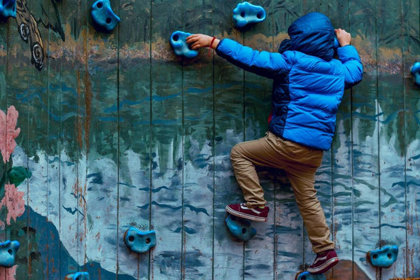 Little boy bouldering on rock climbing wall