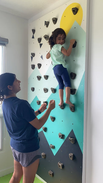 Toddler climbing kids climbing wall with supervision