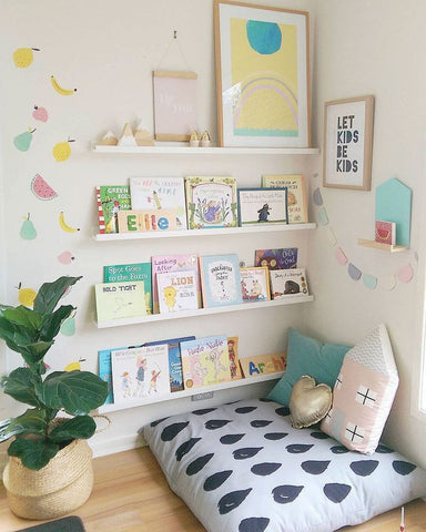 kids reading corner with books, bookshelf, raindrop style cushion, and a plant