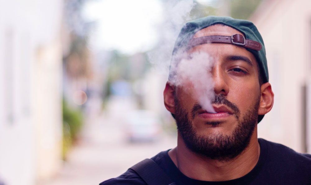 Man vaping in front of city walk