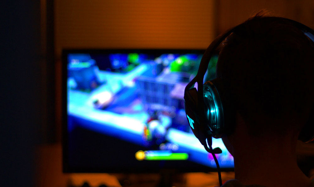 Person with headphones gaming in front of computer monitor