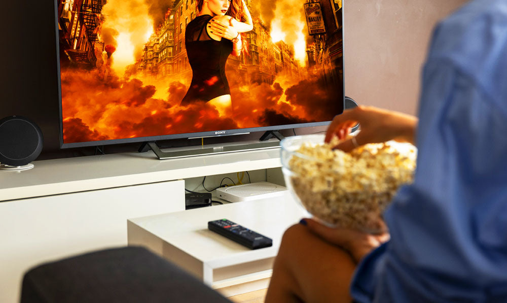 Person watching a movie with popcorn in hand and remote nearby