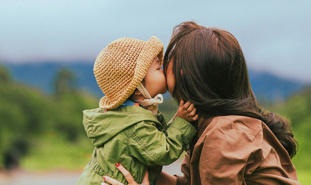 Mother and daughter share a kiss at a field