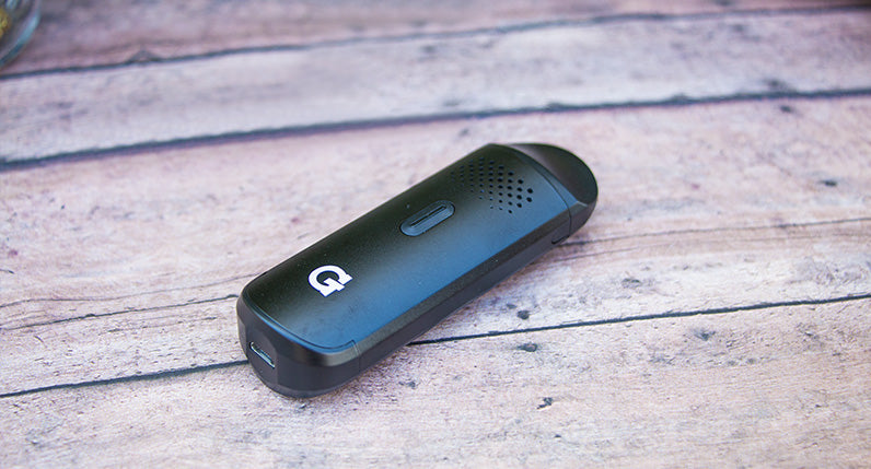 G Pen Dash Dry Herb Vaporizer laying down on wooden table outside.