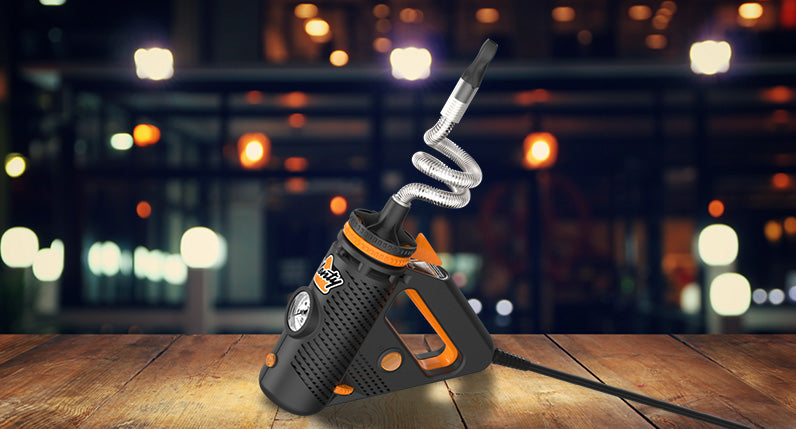 Storz and Bickel Plenty Vaporizer side view with cord standing on wooden platform with street lights