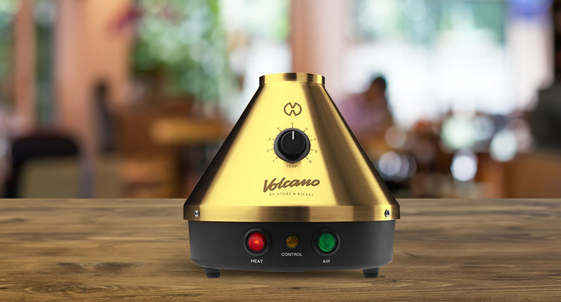 front view of the Storz & Bickel Classic Volcano Gold Edition on wooden table inside coffee shop.