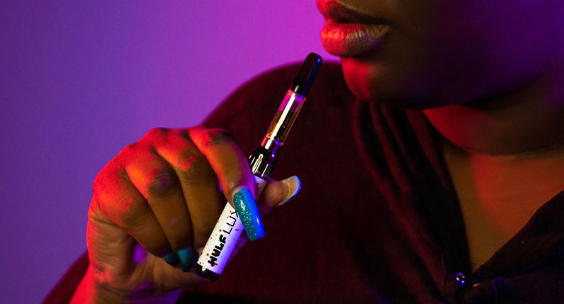 Woman in black jacket holding the Wulf LUX inside studio with purple background