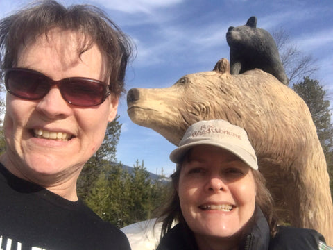 Bear Sentry sisters Cynthia and Kate Gentles in front of grizzly and her cubs sculpture, where bear viewing riverboat tours are launched on the Fraser River, Robison Valley BC.