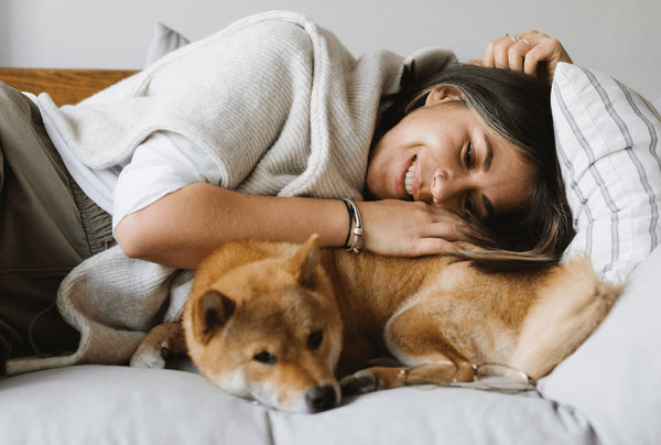 a dog cuddling on a couch with its owner