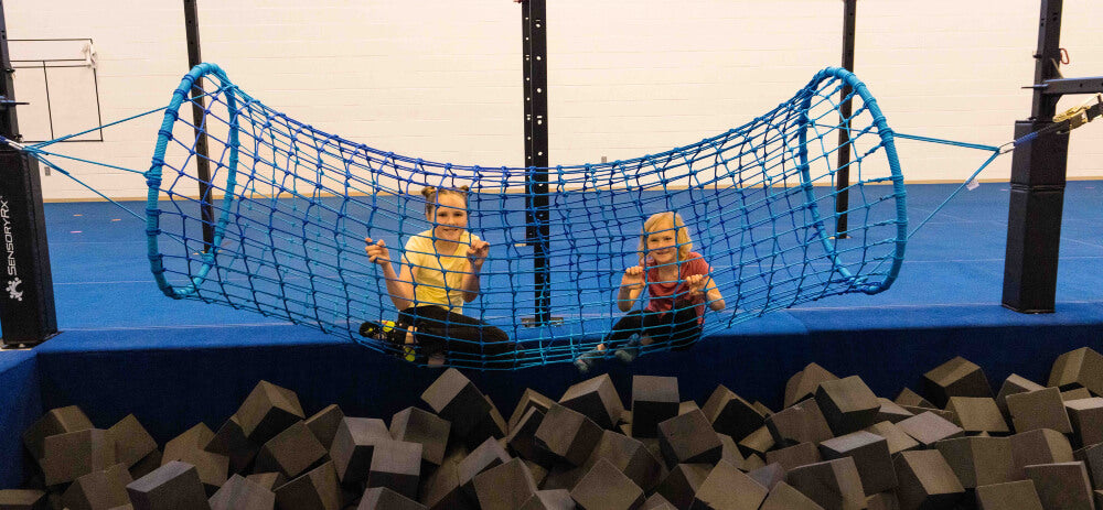 two kids playing in a blue rope tunnel