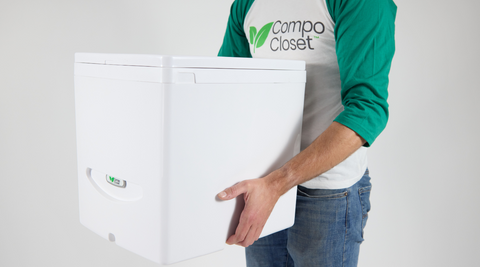 Cuddy lite composting toilet being carried from Richard in a green and white raglan t-hirt with CompoCloset logo on the front