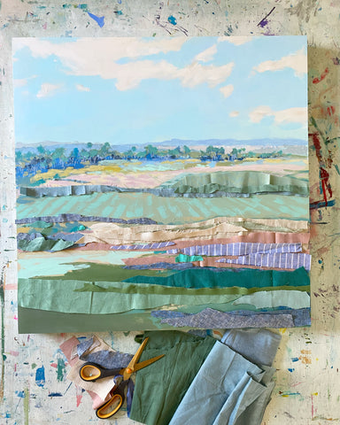 Image: an unfinished landscape by Karin Olah with a bright blue sky and layers of green fabric before they are glued.