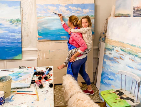 Karin painting with her daughter on her back.