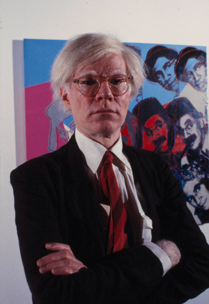 Andy Warhol posant devant un de ses tableaux