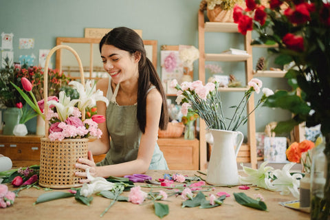 Cheerful woman decorating bouquet in a basket