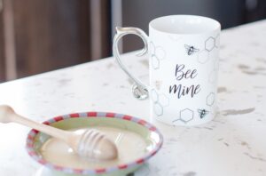 Raw honey next to a mug of tea or coffee