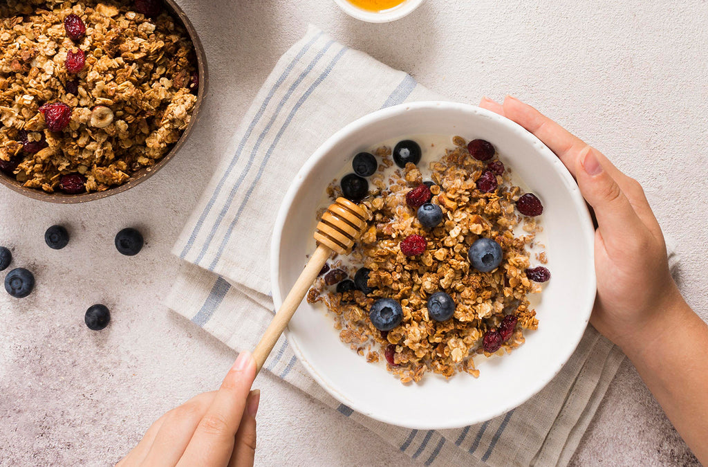 Honey breakfast bowl with granola dried raspberries and blueberries