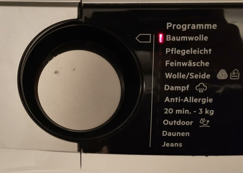 Programmwahlknopf einer Waschmaschine. Rechts neben dem Knopf ist eine Reihe von LEDs. Die oberste LED leuchtet rot, daneben steht Baumwolle geschrieben.