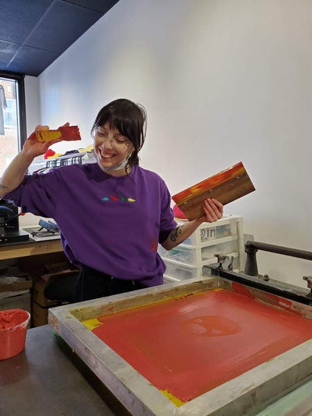 Audrey smiling doing screen printing at Studio Intik