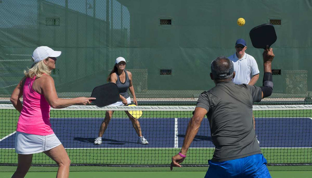 A mixed doubles pickleball match in action.