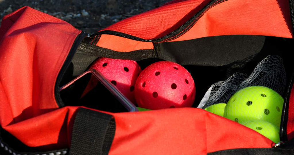 A pickleball and other items are visible in an open pickleball bag.