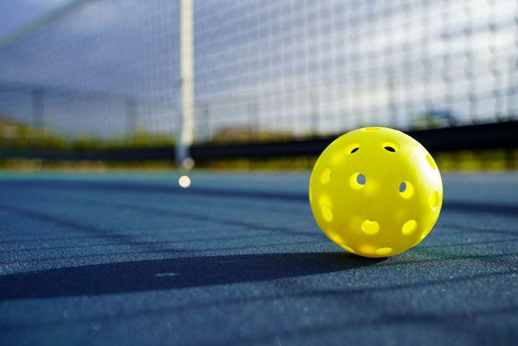 A pickleball on the court in front of the net