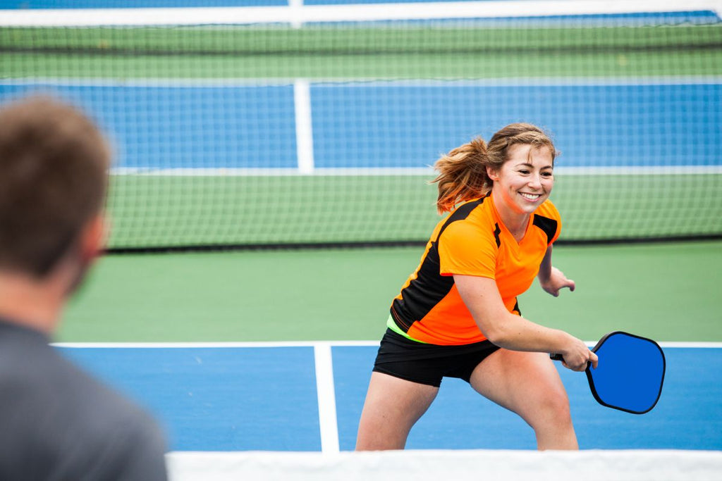 A pickleball player crosses the court to return the ball.