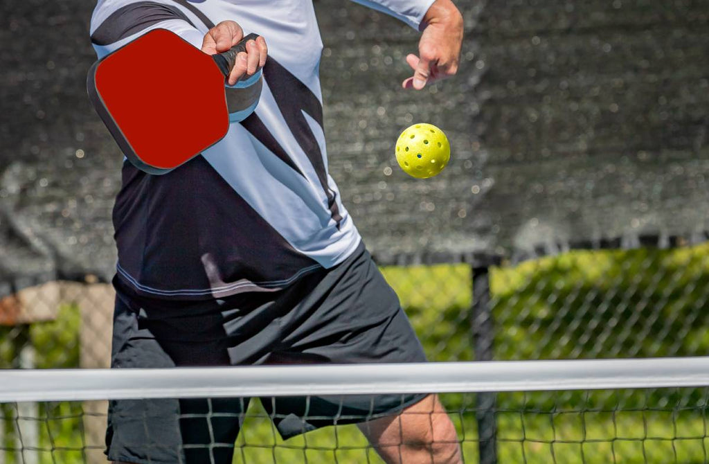 A pickleball player reaches to hit a volley.