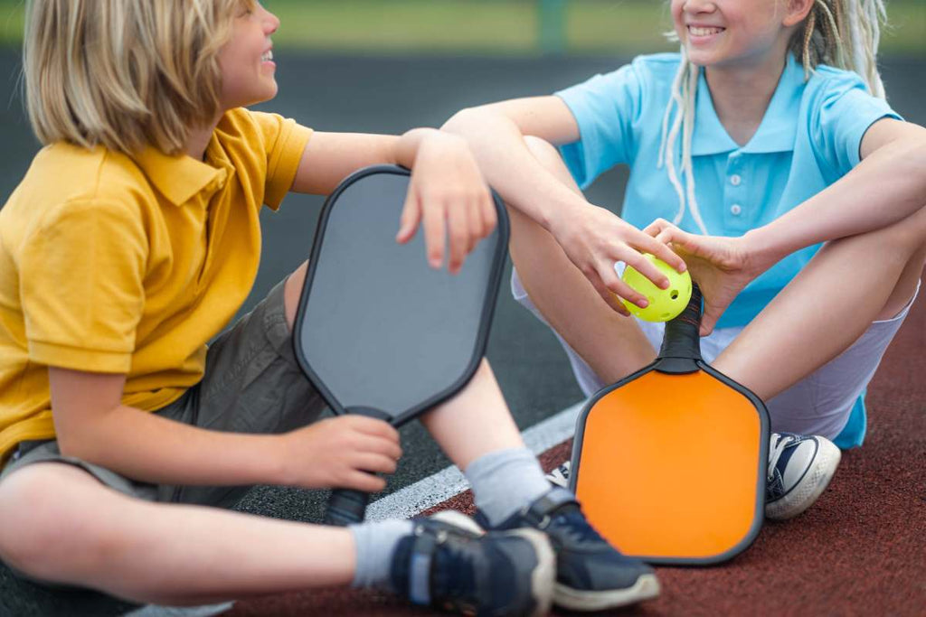 Two children relax on their school’s pickleball court