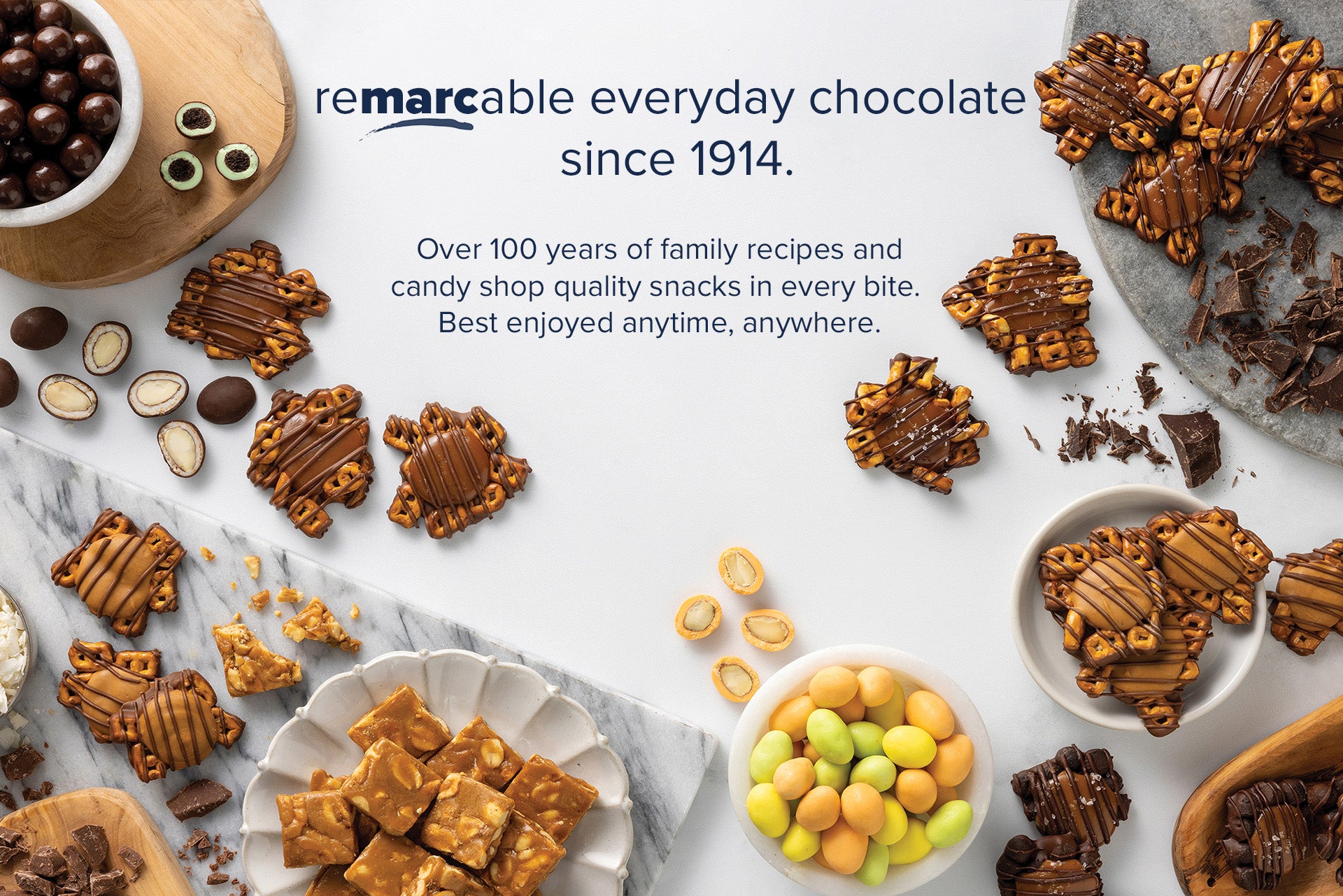 Remarcable everyday chocolate since 1914.  Over 100 years of family recipes and candy shop quality snacks in every bite. Best enjoyed anytime, anywhere.  Overlaying an image of Two decorative ingredient swirls. One contains dark chocolate, coconut and almonds. The other contains caramel, pretzels, and chocolate bits.