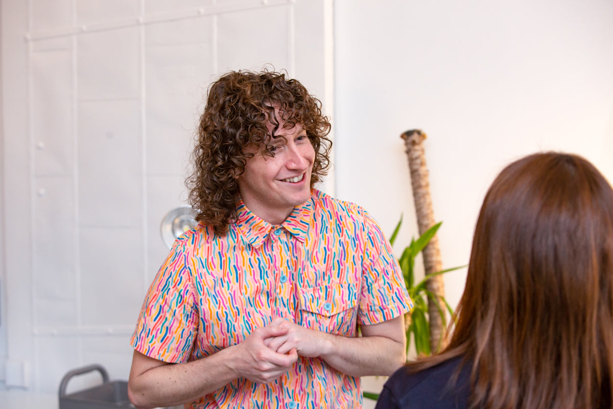 WideFormat: Person greets guest during conversation at coffee lab. 