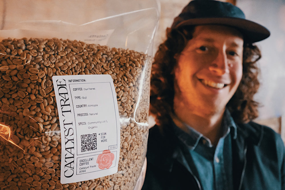 WideFormat Catalyst employee holds bag of green coffee in foreground