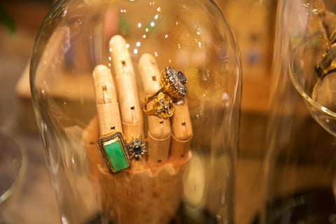 Arman rings displayed on wooden hand under glass bulb