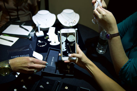 Photo of iphone taking a photo of diamond necklaces on table full of jewelry 