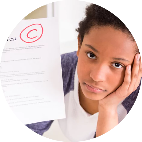 A student looking unhappy and holding a test graded with a C.