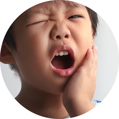 A child holds their cheek, appearing to be in pain.