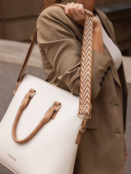 woman holding a vanilla laptop bag with a camel coloured chevron strap