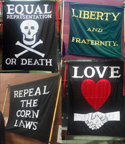 Four flags from Peterloo, with slogans Liberty and Fraternity, Equality or Death, Repeal the Corn Laws, and Love