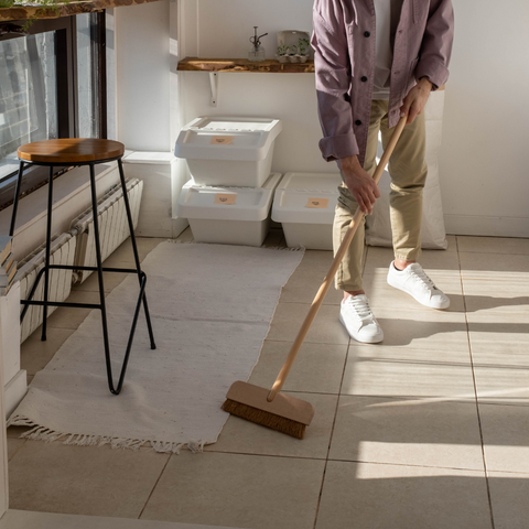 Man sweeping pale tiled floor