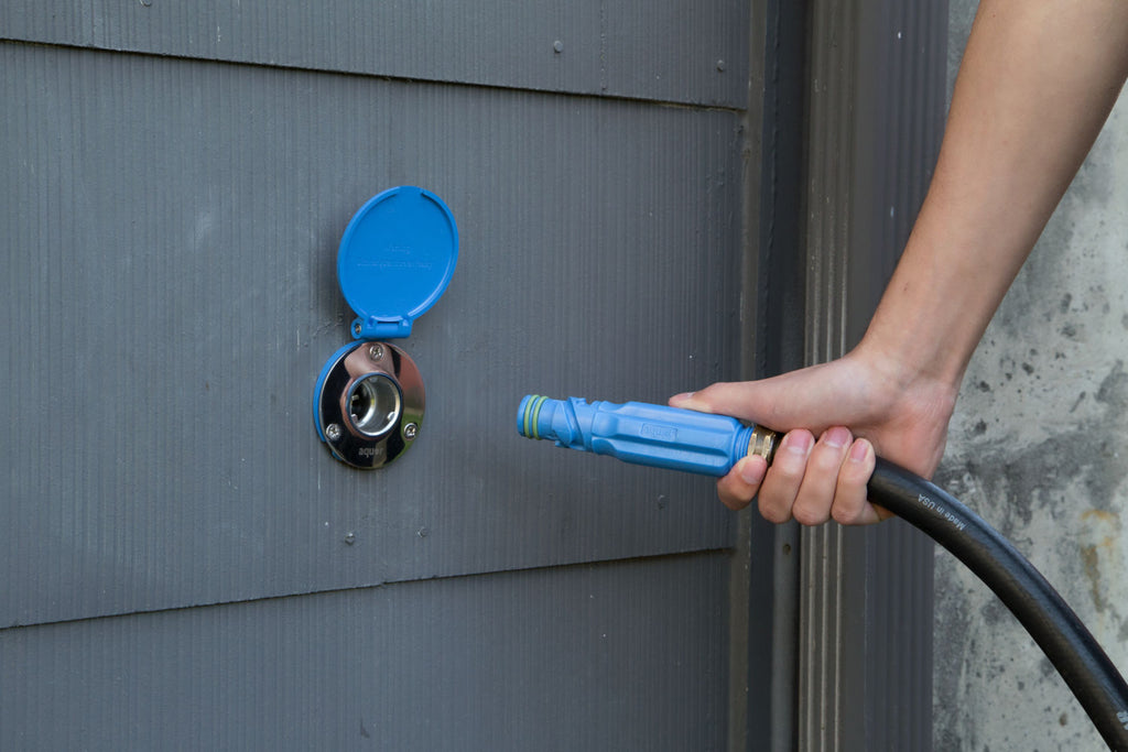 Man plugging into Aquor Blue House Hydrant V1 with Aquor Blue Straight Connector on a dark gray house