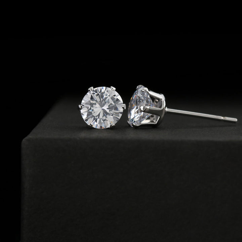 A pair of cubic zirconia tops that have been placed on a black surface against which the two stones are shining brightly.
