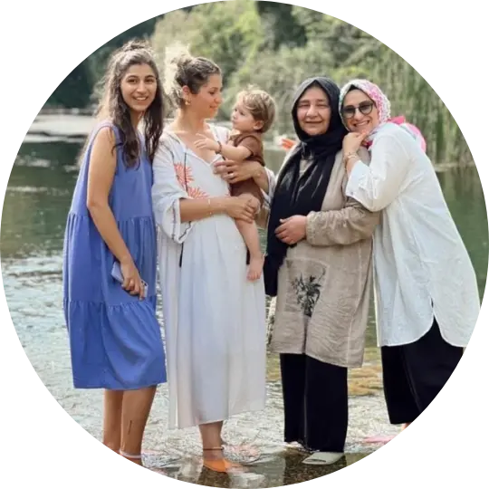 Four women and a child standing by a river, smiling.