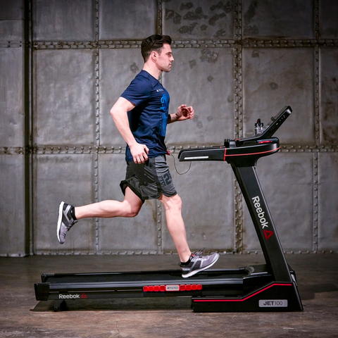 A young man running on a treadmill in a garage themed space