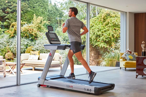 Man running on a treadmill at home facing the garden