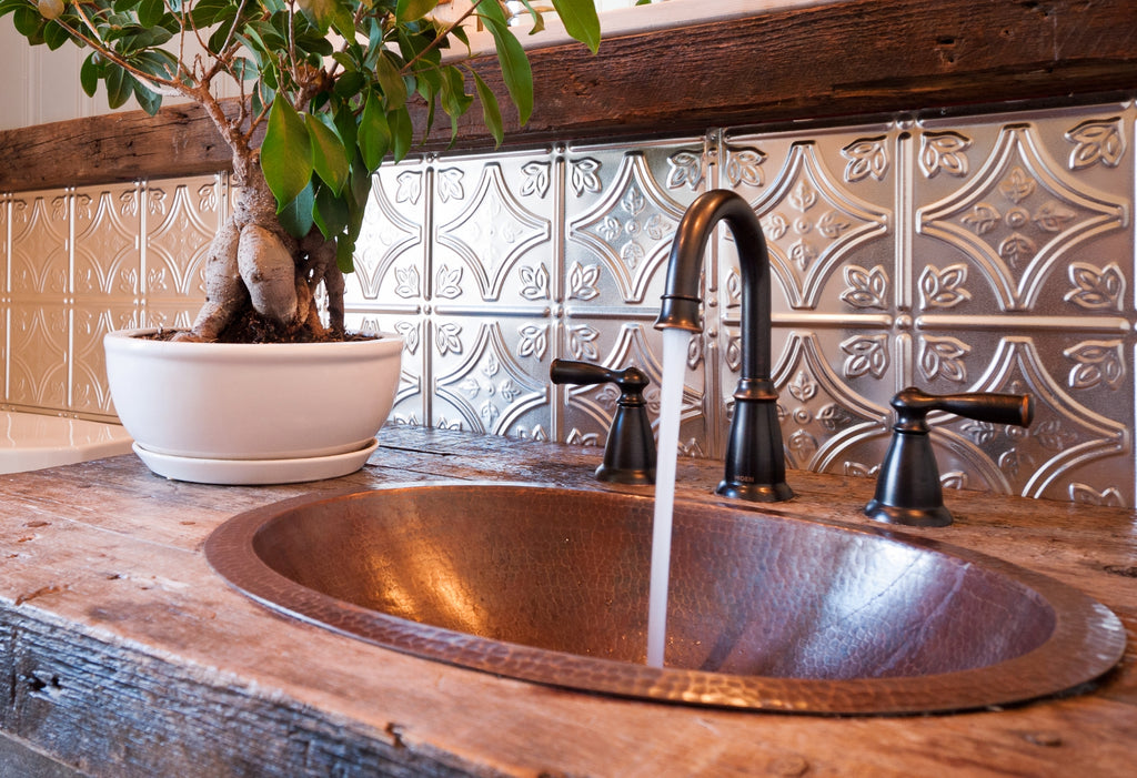 Copper sink and tin tiles on the backsplash in an ensuite bathroom.