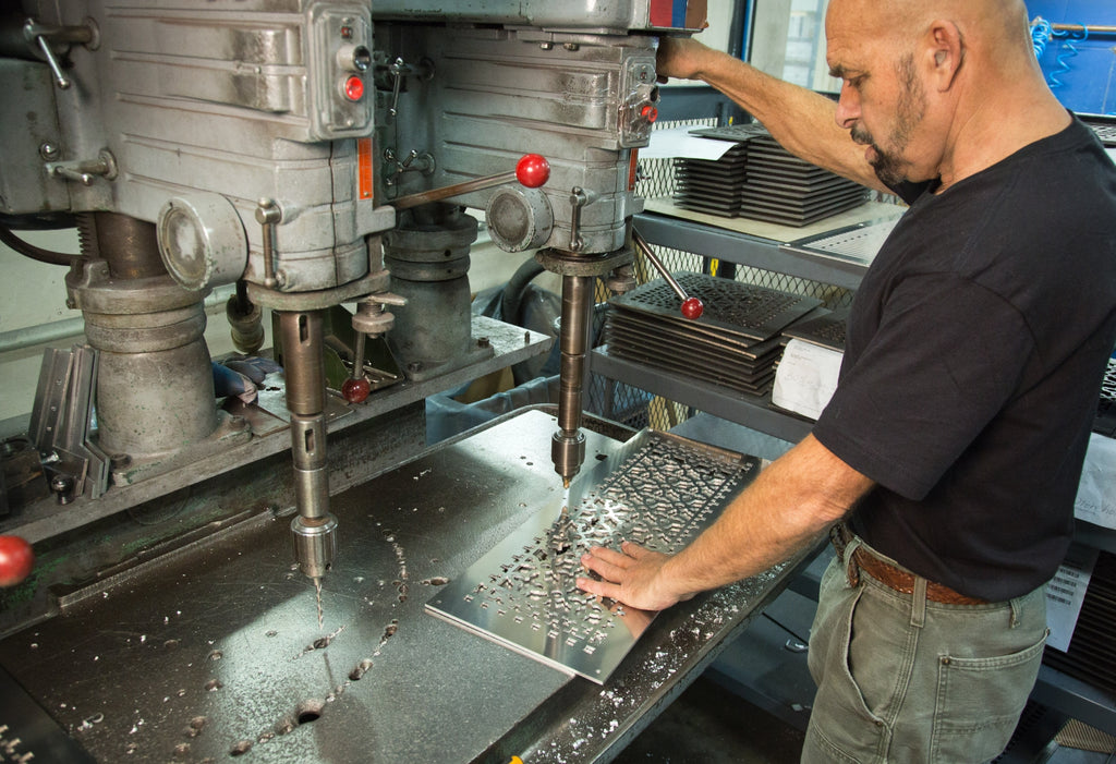 Person drilling holes in a vent cover at the Reggio facility.