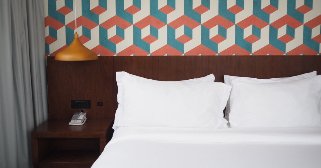 Geometric wall paper behind a bed.