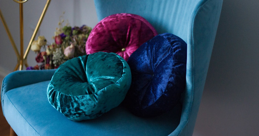 Blue chair with velvet multi-colored pillows.