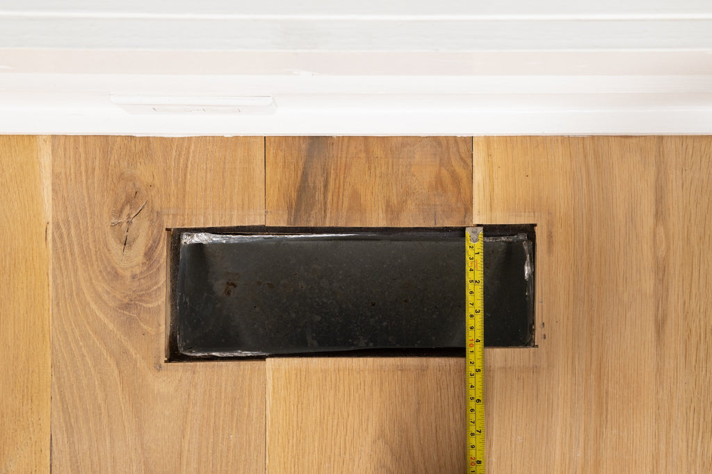 Floor vent with cover removed being measured for width.