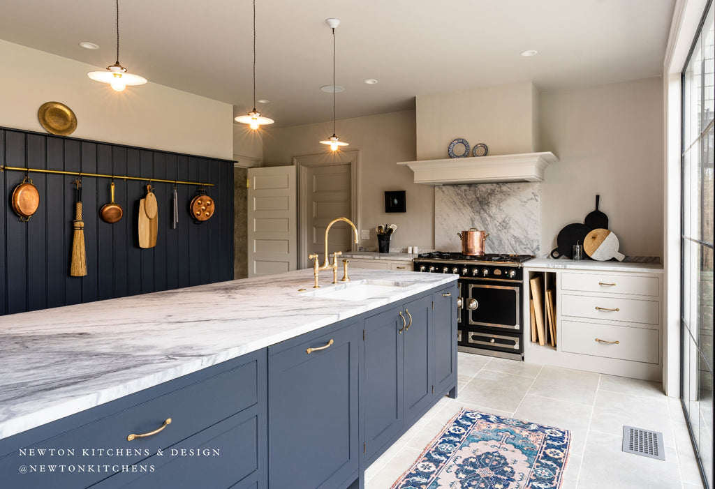 Large kitchen with blue cabinets and copper pans hanging on the wall.